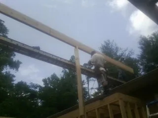 Carpenter setting a ridge beam over a new addition frame — Ice Dam Removal by Roofing Brothers in Port Neches