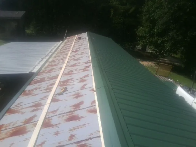 Old rusted panels beside newly installed green metal roofing — Wind Damage Roof Repair by Roofing Brothers in Port Neches