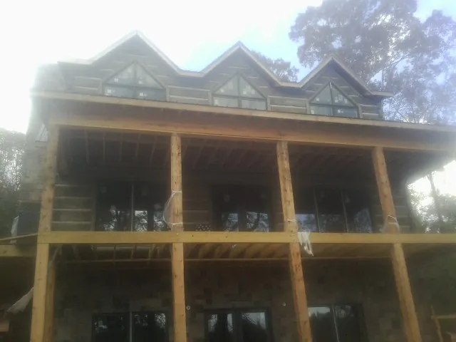 Dormers and porch framing on a large log home under construction — Roof Coating work by our crew in Port Neches