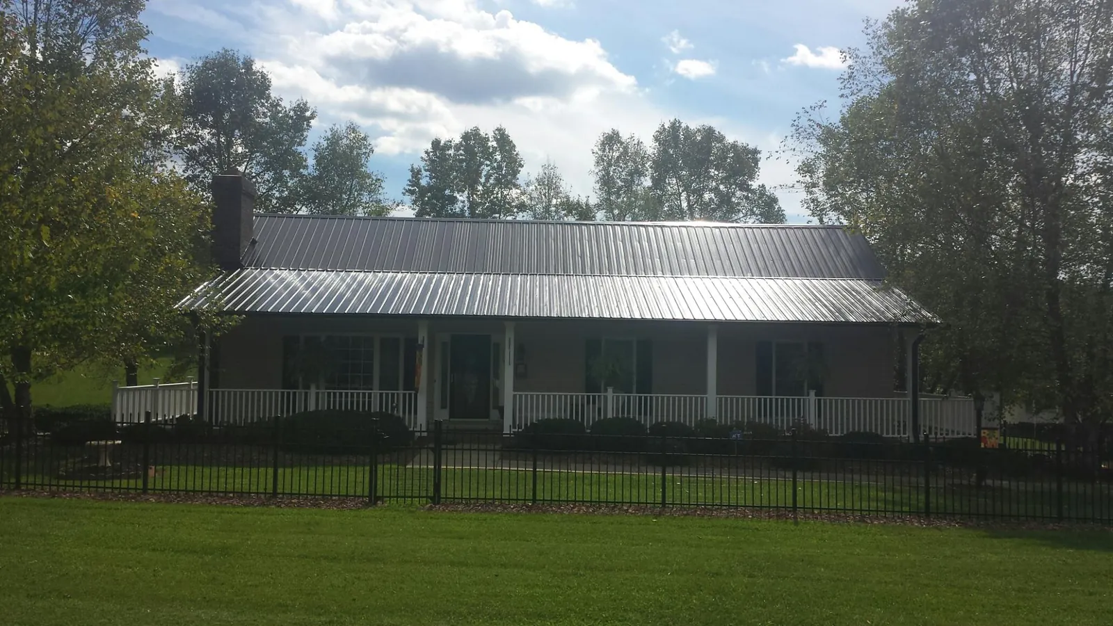 Gray metal roof on a brick ranch with a full width front porch — Gutter Guard Installation work by our crew in Port Neches