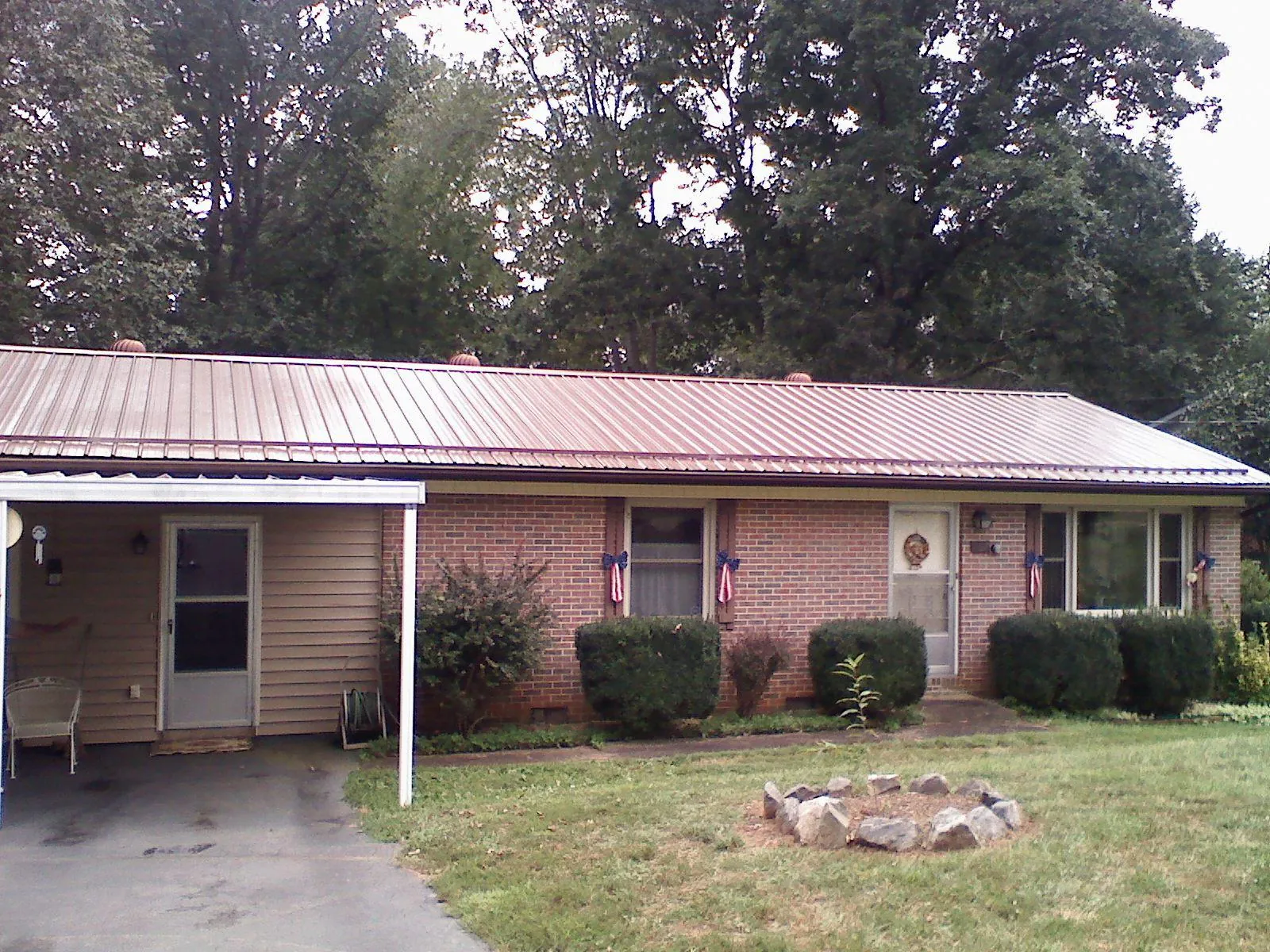 Bronze metal roof and carport on a brick ranch home — Roof Repair work by our crew in Port Neches