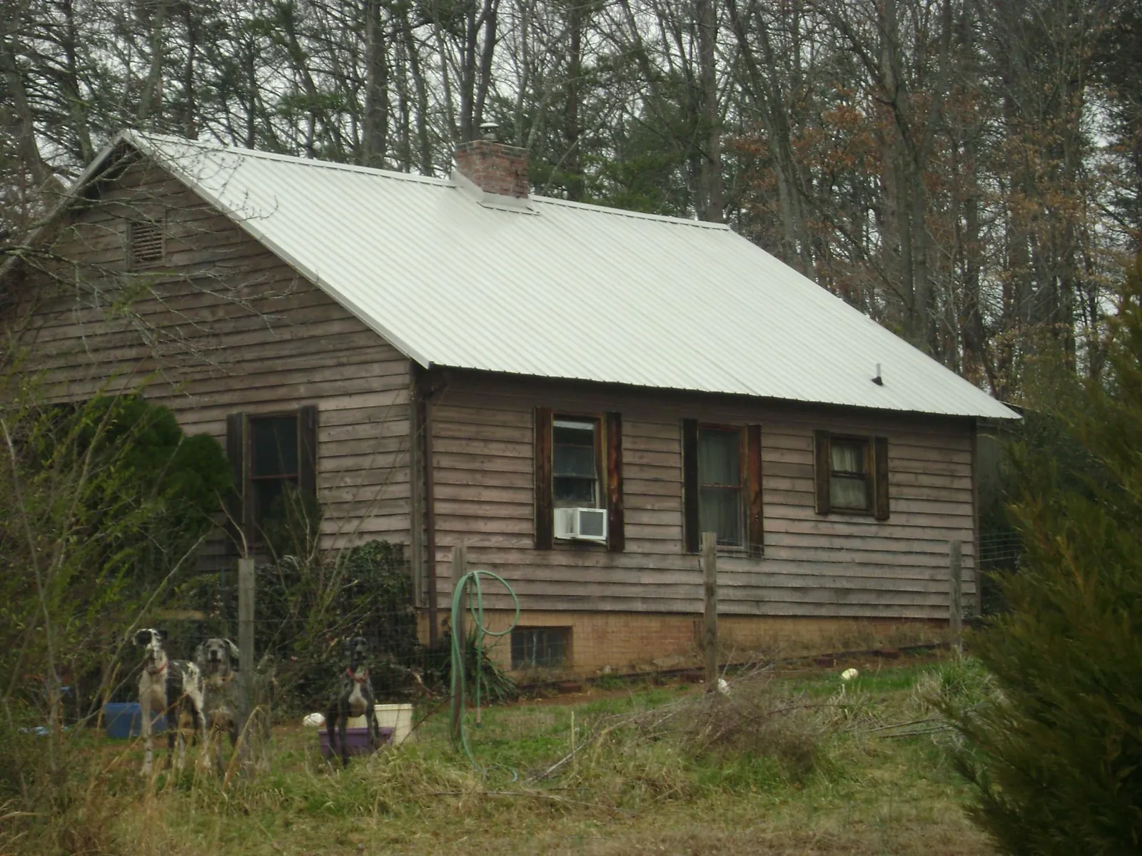 White metal roof on an old wood sided farmhouse, from a Metal Roof Installation job in Port Neches