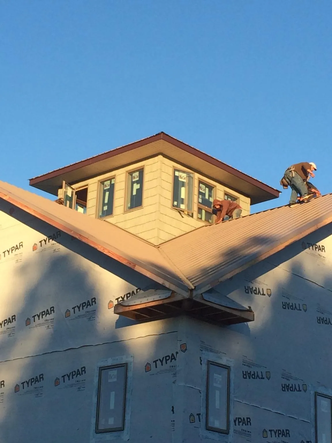 Roofers working around a rooftop cupola on a new metal roof at sunset — Roof Waterproofing in Port Neches by Roofing Brothers